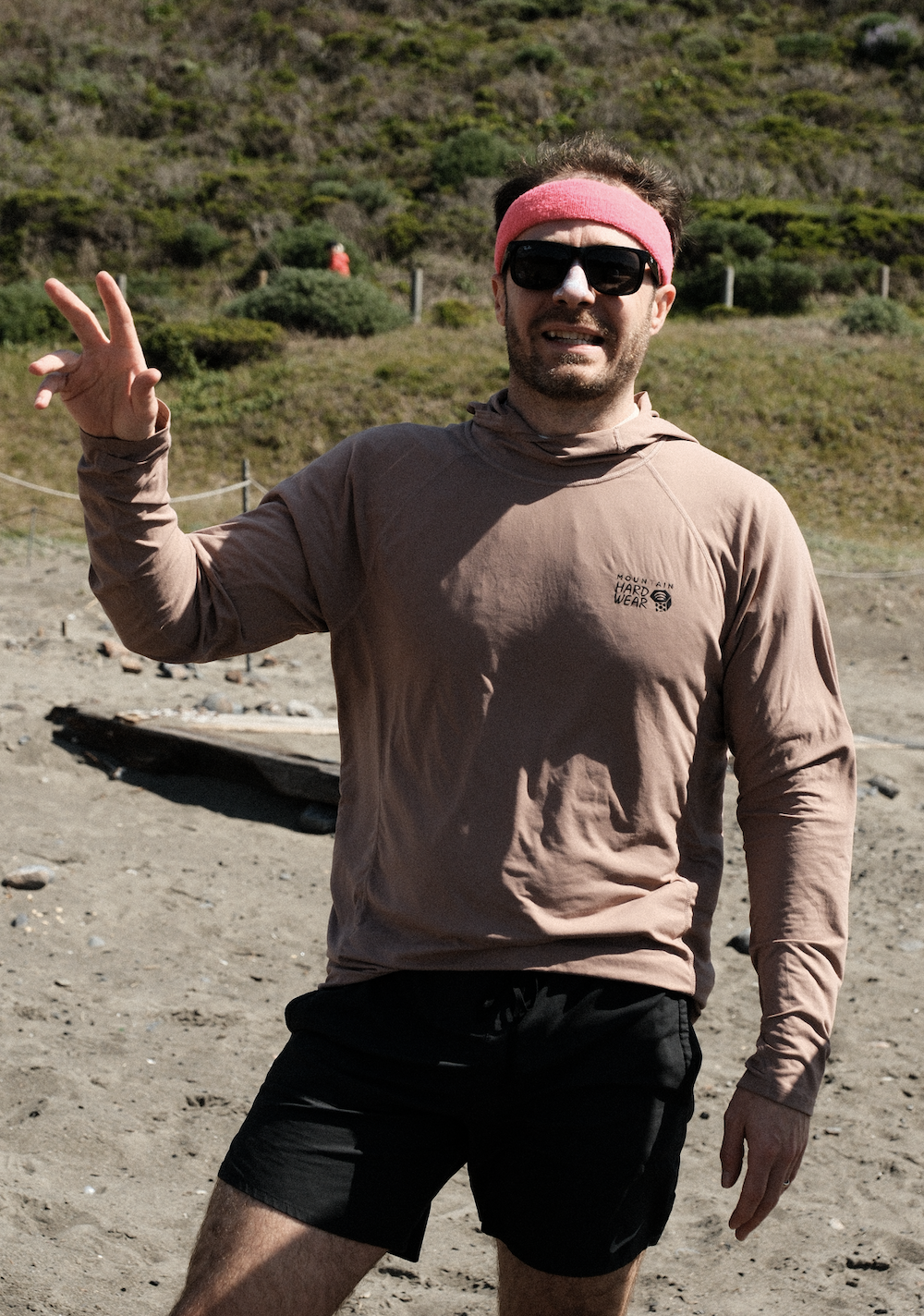 Randy showing a peace sign with his signature pink headband and sunglasses